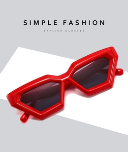 Detail of red geometric polygon sunglasses with dark lenses on a minimalist background