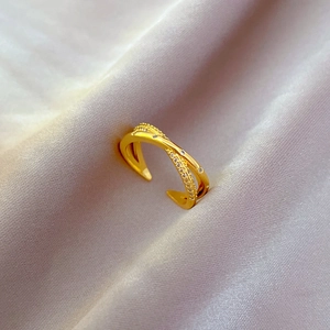 Detailed view of gold plated crisscross adjustable ring with zircon accents on silk