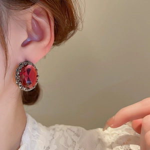 Vintage oval red gemstone studs with dark metal frame worn on model for elegant style