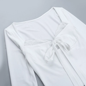 Detailed view of white long-sleeve top featuring lace trim and bow-tie neckline design