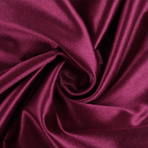 Macro du tissu satiné rose rouge montrant une texture luxueuse et un drapé élégant