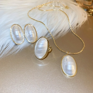 Vue détaillée du collier, boucles d'oreilles et bague en perles plaquées or sur peluche