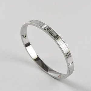 Detailed close-up of musical note engraving on a silver stainless steel bangle