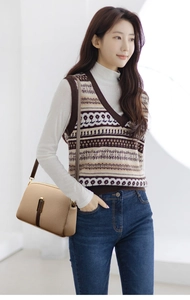 Model wearing a minimalist beige leather crossbody bag with a brown strap and metal clasp