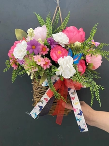 Detail of hanging basket with artificial peony, daisy flowers and decorative ribbons