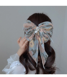 Détail de la pince à cheveux noeud en mousseline florale avec perles élégantes bleues