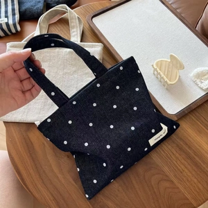 Detailed close-up of dark blue polka dot denim tote bag with white simple wish label