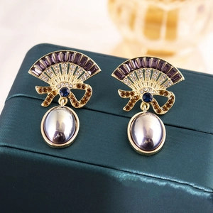 Detail of vintage fan-shaped earrings with purple gems and elegant oval pearls