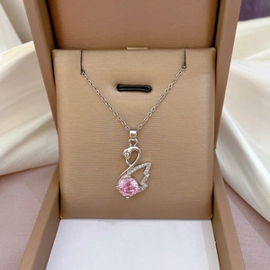Close-up of a silver swan necklace with pink gemstone and zircons in a brown gift box