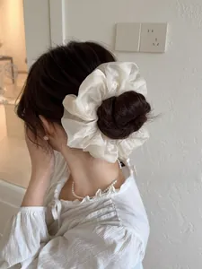 Dettaglio dell'elastico scrunchie gigante in organza bianca indossato su uno chignon