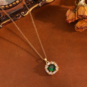 Detail einer Vintage-Goldhalskette mit großem grünem Stein und Zirkon-Halo