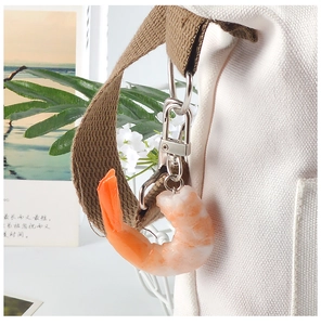 Realistische PVC garnaal sleutelhanger hangend aan een witte canvas tas schouderriem