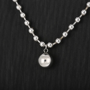 Close-up of a silver stainless steel ball pendant on a matching bead chain jewelry
