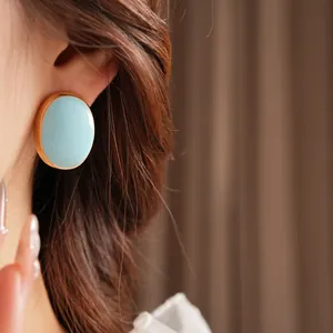 Vintage oval blue enamel earrings with gold trim worn by a model in French retro style