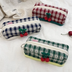 Detail of plaid canvas pouches with handmade knitted cherry zipper pulls and side labels