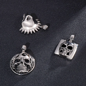 Three vintage silver skull pendants in diverse gothic designs on black background