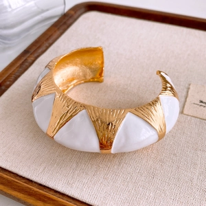 Detail of vintage gold-plated cuff bangle with hammer finish and white enamel inlay