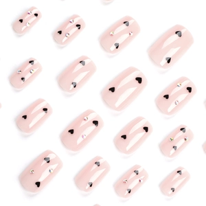 Pink square press-on nails with black spade hearts and sparkling rhinestones