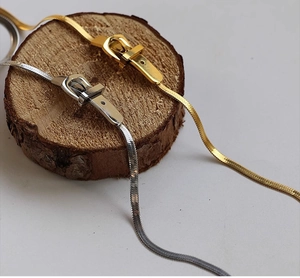 Close-up of gold and silver belt buckle design necklaces on a rustic wood stand