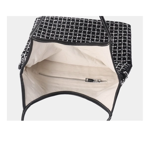 Interior detail of black studded tote bag featuring beige canvas lining and zipper pocket