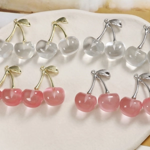 Macro detail of transparent cherry charms with metal leaves for DIY jewelry making