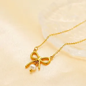 Minimalist gold bow necklace with white pearl pendant on silk fabric background