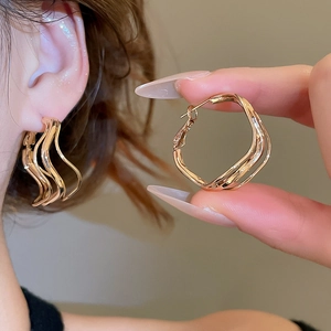 Detail view showing layered gold wavy hoop earrings on model and as close-up product shot