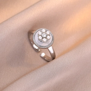 Silver flower ring with white pearls and zircon on beige silk background