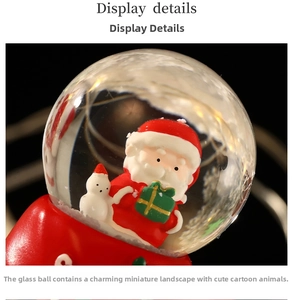 Détail macro d'une boule à neige de Noël avec Père Noël et bonhomme de neige sur socle rouge