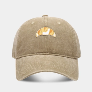 Close-up of a vintage khaki cotton baseball cap with detailed croissant embroidery