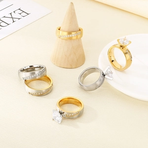 Elegant gold and silver stainless steel rings with sparkling cubic zirconia on a stand