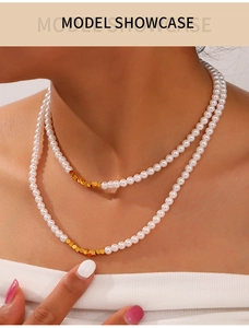 Double-layer faux pearl necklace with gold cube accents on a model's neckline