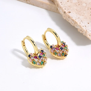 Macro detail of gold hoop earrings with heart charms and colorful pave crystals