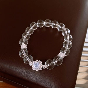 Detail of beaded crystal bracelet with zircon floral charm and clear gemstone on leather