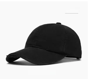 Close-up of distressed ripped details on a black cotton baseball cap in streetwear style