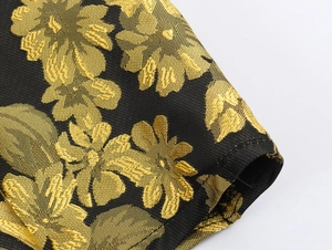 Detalle macro de tela jacquard negra y dorada con textura de hilo metálico de calidad