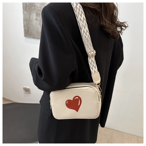 Detail of cream crossbody bag with red heart pattern and geometric wide strap