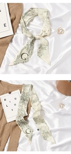 Detail of elegant beige and green skinny silk scarf with botanical print and G letter