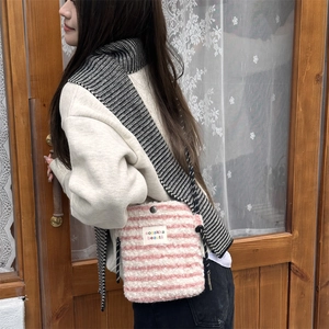 Detail of pink and white striped plush crossbody bag with metal snap and logo label