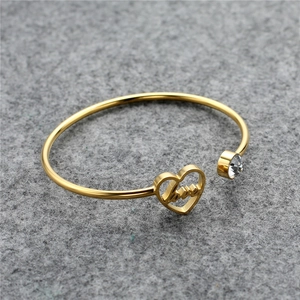 Macro shot of gold heart bracelet featuring LOVE engraving and a sparkling zircon