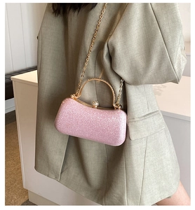 Close-up of soft pink glitter evening bag with gold metal handle and chain strap on model
