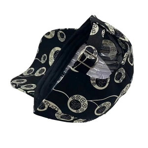 Detail view of the adjustable metal buckle on black baseball cap with clover pattern