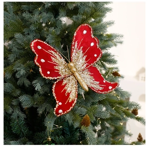 Detail view of red velvet Christmas butterfly ornament with gold glitter on green tree branches