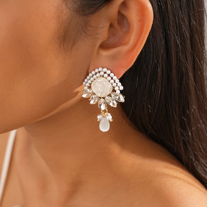 Close-up of elegant gold vintage earrings with resin pearls and clear crystals on a model