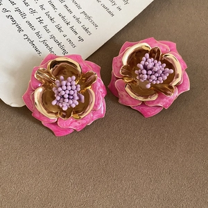 Détail macro de boucles d'oreilles fleurs 3D rose avec base dorée sur papier vintage