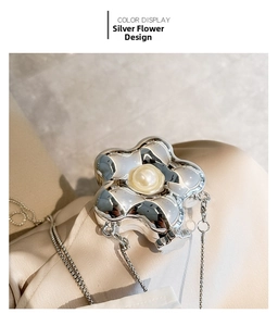 Macro shot of silver flower mini bag with central pearl on silk fabric background