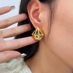 Boucles d'oreilles géométriques dorées à l'or 18 carats portées par un mannequin