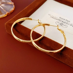Macro view of chunky gold hoop earrings resting on a velvet jewelry tray display