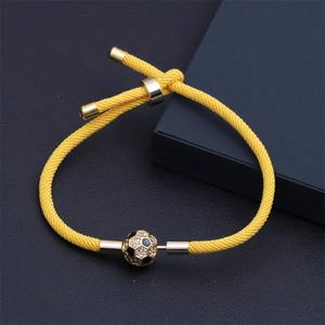 Dettaglio del bracciale da calcio intrecciato giallo con ciondolo in cristallo dorato e cursore