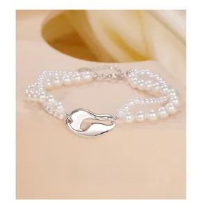 Dettaglio del bracciale a doppio strato di perle d'argento con ciondolo a chicco di caffè